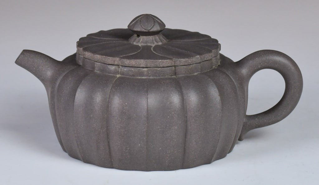 A Lobed Chrysanthemum Zisha Teapot: Known as a Chrysanthemum Petal style. The body is divided into vertical ribs that meet precisely at the lid, extending into a flower-shaped knot. D:18.5cm, H:8.5cm 