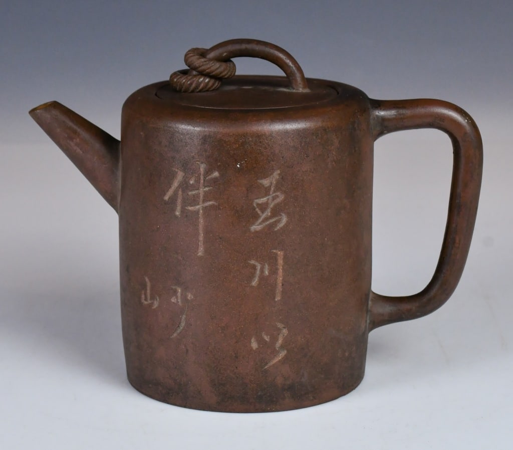 An Inscribed Stone Pillar Zisha Teapot 19thC: A straight, cylindrical body with a flat top and base. Features a Rope-Twist knop on the lid, exterior is incised with a calligraphic inscription in a free, artistic script. Maker's mark at the