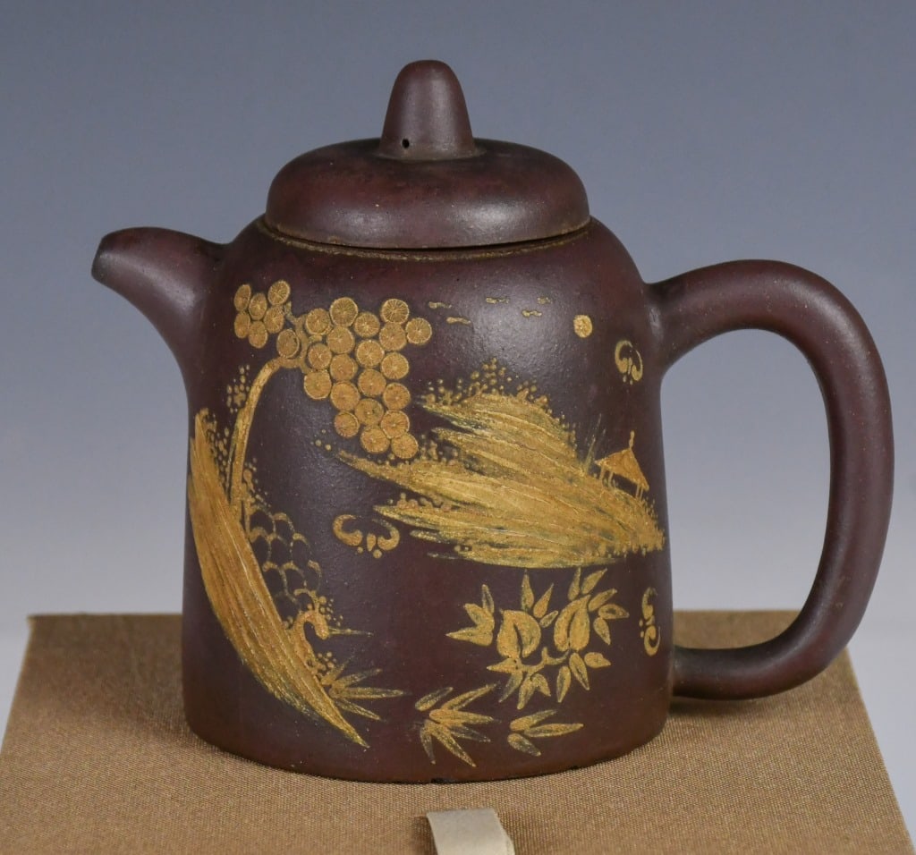 A Color Mud Painting Zisha Teapot w/box: A classic cylindrical body, deftly embellished with buff-clay painting. The scene depicts an intricate landscape featuring pine tree, stylized rockery, and distant mountains, evoking a sense of 