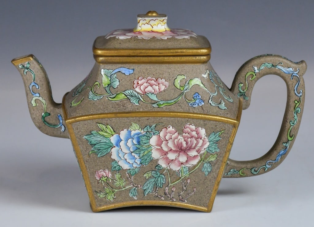 A Enamelled Zisha Peony Square Teapot: A square-shaped zisha teapot with a matching flat lid, decorated with hand-painted peonies in vibrant pink, blue, and yellow. The handle and spout are accented with delicate leaf patterns and 