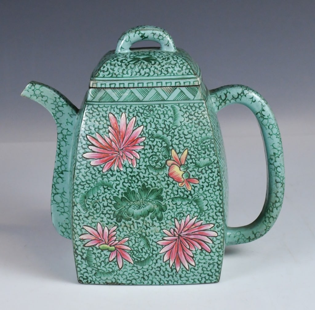 An Enameled Hanfang Zisha Teapot 19thC: A classic Han-style square form, the vessel is surmounted by a bridge-shaped knot and balanced by a curved spout and a circular handle. The body is decorated with floral motif on a turquoise-green gro