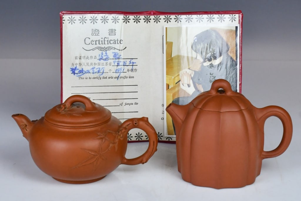 Group of 2 Zisha Teapots w/1 Certificate: Comprising 2 Zisha teapots, crafted from rich, bright red clay, in various styles and sizes. H:9.8cm, with certificate; The other one D:15cm. With marker's mark at the bottom 