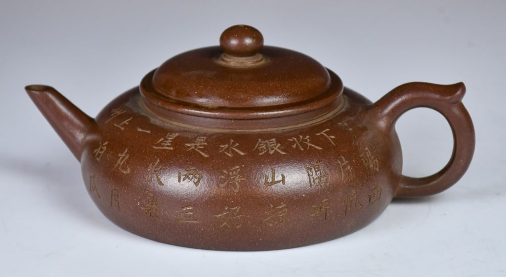 An Inscribed Virtual Flat Zisha Teapot: A classic virtual flat shape, the vessel is surmounted by a matching domed cover with a subtle bead knop, balanced by a slender, upward-tapering spout and an elegant C-shaped handle with a small "flyi