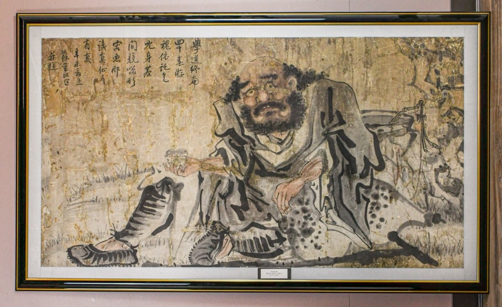 Anonymous Figural Story: Ink and light color on paper, framed, depicted a Taoist priest in a long robe sitting with a cup in his right hand. Upper corner with artist's inscription and signature. Painting:77.3x141.1cm; 