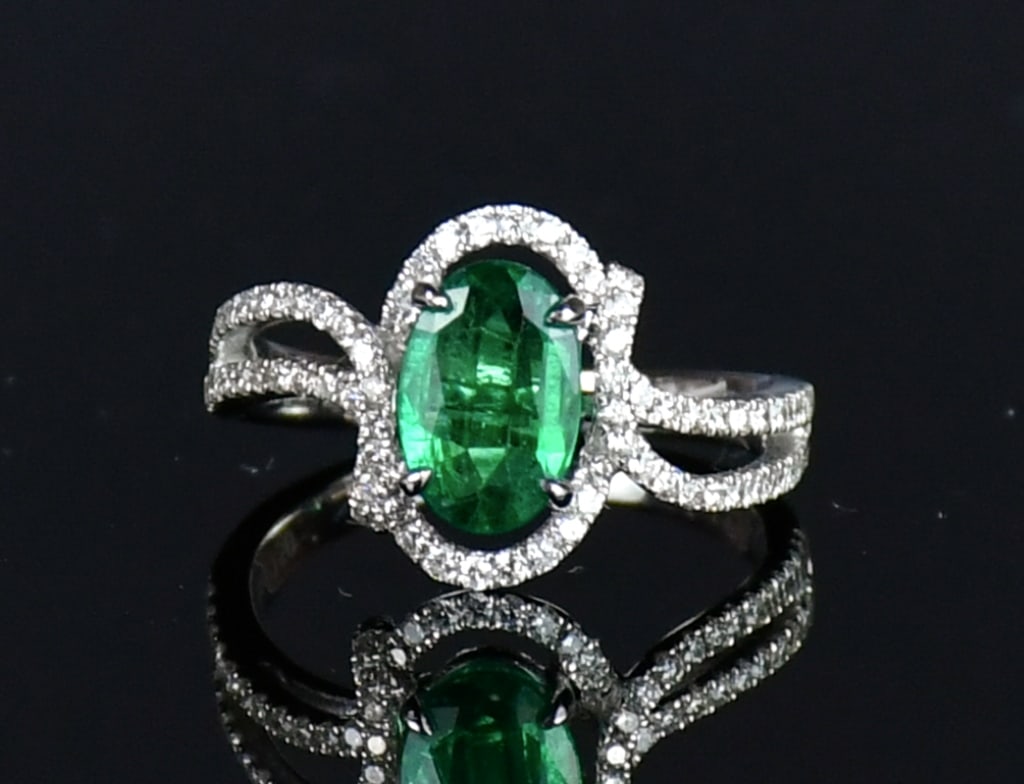 A Emerald & Diamond Ring: A stamped AU 750 (18K) white gold casted emerald and diamond ring, contains 1 oval prong set natural emerald spectrum approx 1.12carats with diamonds, size:US 6. Comes with certificate and purchase re