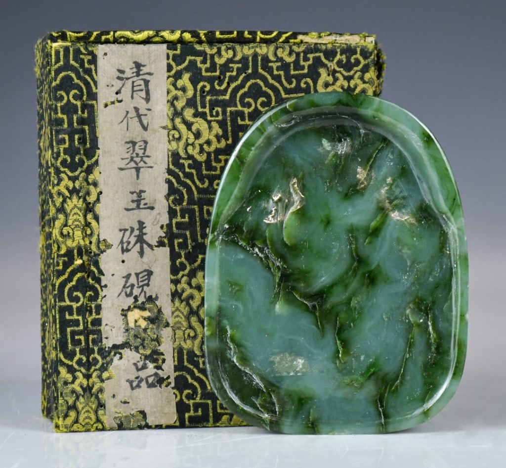 A Green Jade Ink Stone w/Box Republican: Of oval form, overall in a grass-green color with darker veinings. 10.5cm x 8cm. Comes with box 民國 翠玉硯台 連盒