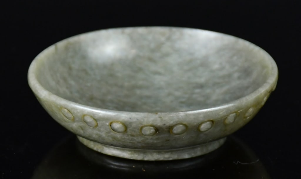 A Greyish Green Jade Stone Dish Republican: The rounded sides rising from a short foot, exterior near the rim decorated with a line of small poke dots, D:6.5cm 民國 青玉文房小碟