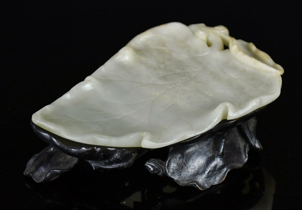A Pale Celadon Jade Leaf Shape Dish w/Std Qing: A flattened leaf shape dish, the stone overall in pale celadon color tone, 11.2x8cm, comes with a matching wood carved stand 清 青白玉葉形筆掭連&#
