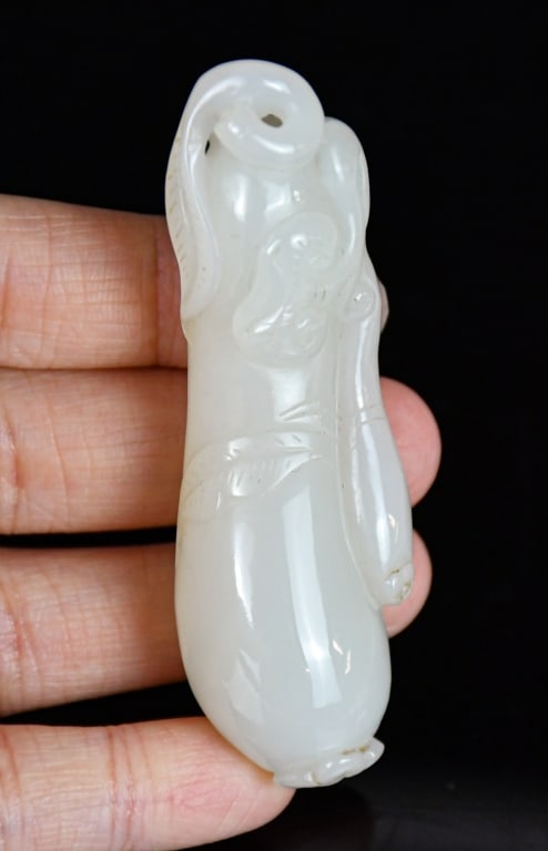 A White Jade Carved Melon Qing: Worked as a large melon borne on curling tendrils issuing smaller melon on a gnarled branch issuing leafy curling tendrils. L:7.2cm 清 白玉雕福瓜把件