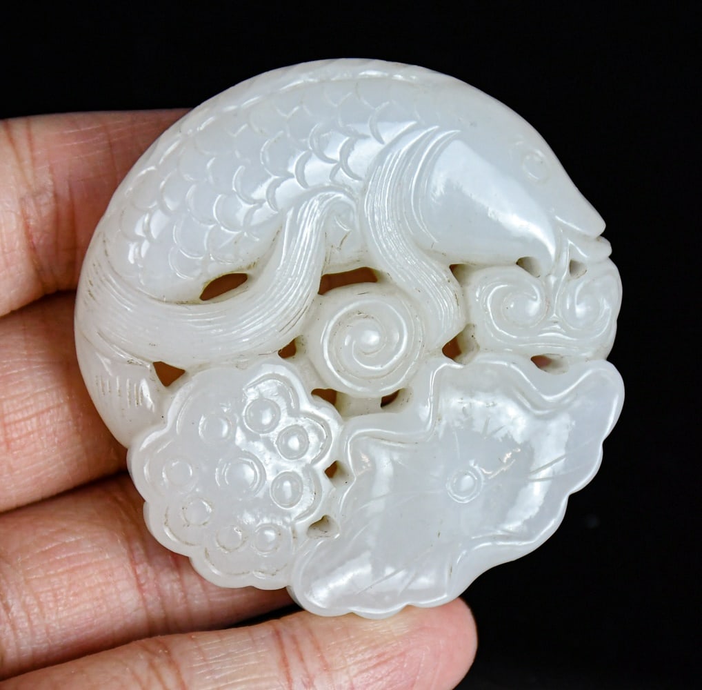 A White Jade Carved Lotus & Carp: A jade carved carp, lotus leaf and pod, the stone overall in rice white color, D:5.2cm 民國 白玉雕年年有餘圓珮