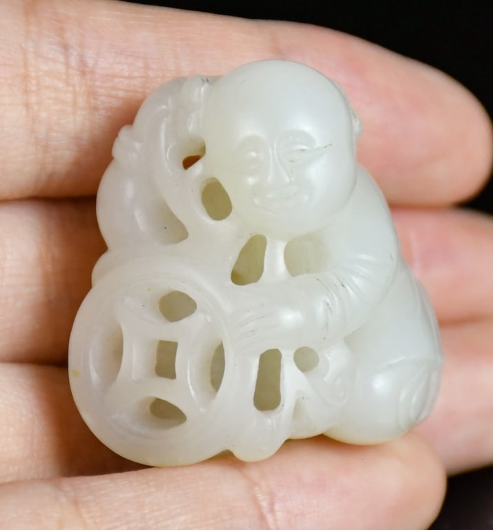 A White Jade Figural Carving: A white jade carved boy with coin, the stone overall in white color tone, H:3.2cm 白玉雕運財童子把件