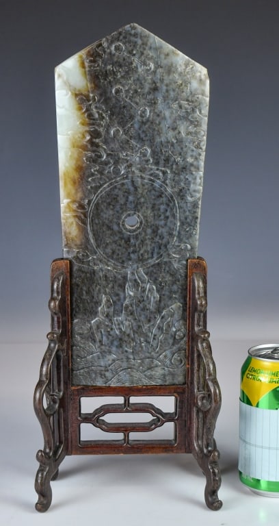 An Archaistic Carved Jade Ritual Blade: Carved as an elongated tablet tapering slightly toward a pointed apex. It features a central aperture pierced from both sides. The front face is carved in low relief with a central circular disc, supp
