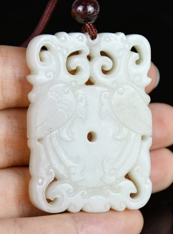 A White Jade Carved Phoenix Plaque Qing: A white jade plaque, with a pair reticulated carved Kui phoenix surrounding a disc theme, the stone overall in rice white color tone. 3.3x4.8cm 清 白玉透雕夔鳳