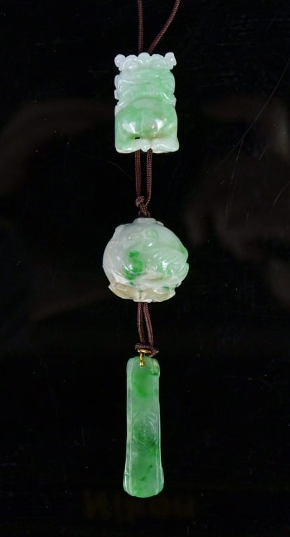 A Group of 3 Jadeite Pendants Republican: Comprising a carved mythical beast, a spherical bead carved in low relief with goose, and an incised slender rectangular plaque (L: 3.9cm), all suspended on a cord. 民國