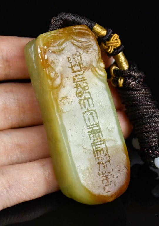 An Archaistic Carved Jade Tiger Tally Pendant: The pendant is meticulously carved in the archaistic form of a tiger tally. The jade utilizes the two-tone coloration. The upper russet portion is finely incised with archaistic inscriptions. 6.1x2.2x