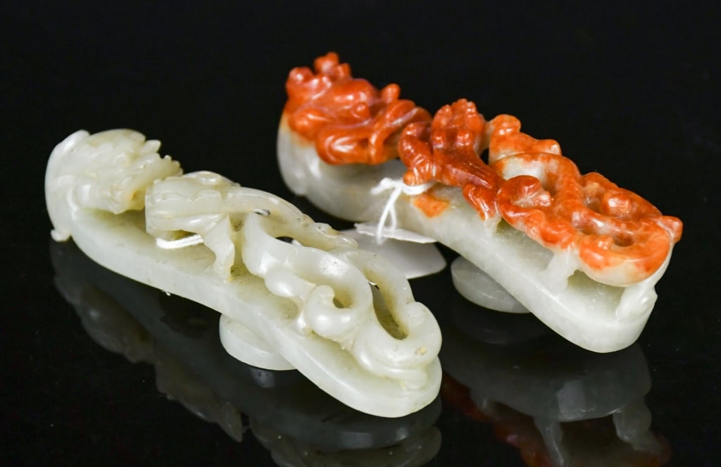 A Jade & A Jadeite Belt Hooks Qing: Comprising two belt hooks, one of pale celadon jade, the other of jadeite with russet-red suffusions, both carved with dragon heads and carved in relief with chilong motifs. Larger L: 8.1cm 清 &