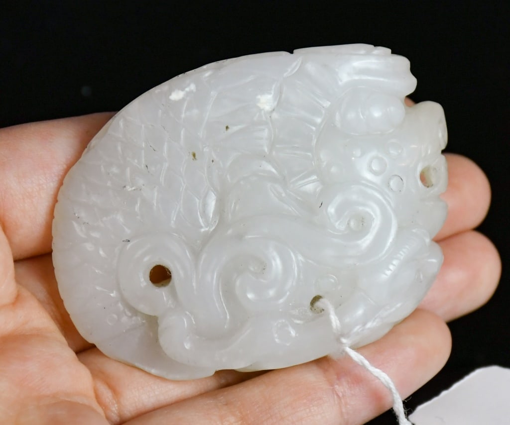 A White Jade Carved Dragon-Head Fish Qing: Carved a mythical dragon-head fish in a recumbent position, the stone overall in white color tone. 4.3x6cm 清 白玉雕魚龍把件