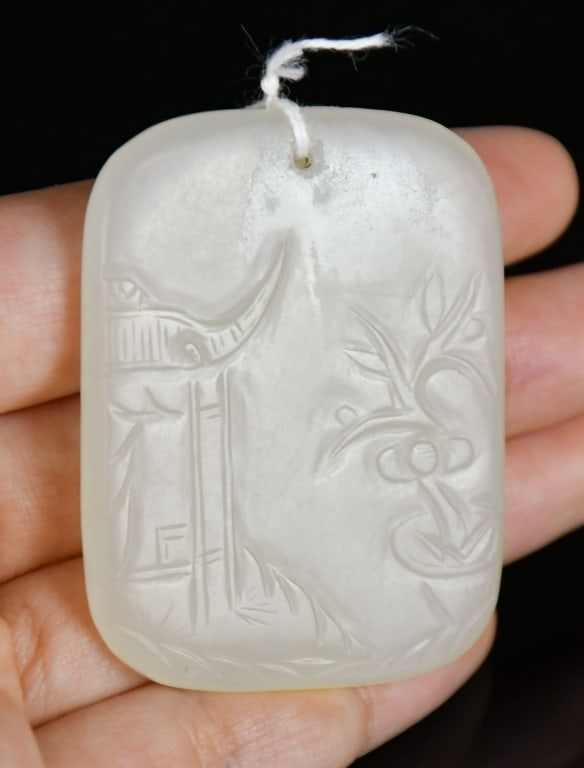 A Celadon Jade Carved Landscape Plaque Qing: The rectangular white jade plaque carved with a landscape scene featuring a pavilion and flowering branches to one side, the reverse with bamboo amidst rockwork, the stone of pale celadon tone. 3.9x5.