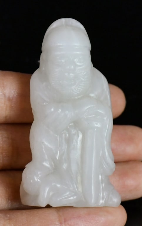 A White Jade Carved Figurine Republican: Carved from a white jade, worked as a single figure holding a sword. 5.6x3.1cm 民國 白玉雕人物把件
