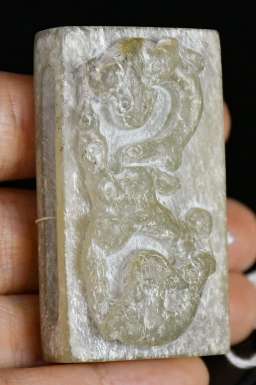 An Archaistic Jade Scabbard Slide: Of rectangular form, carved in relief with two beast to the top surface, the underside with a horizontal slot. The stone of pale celadon and white tone. 4.9x2.8cm 高古風格 