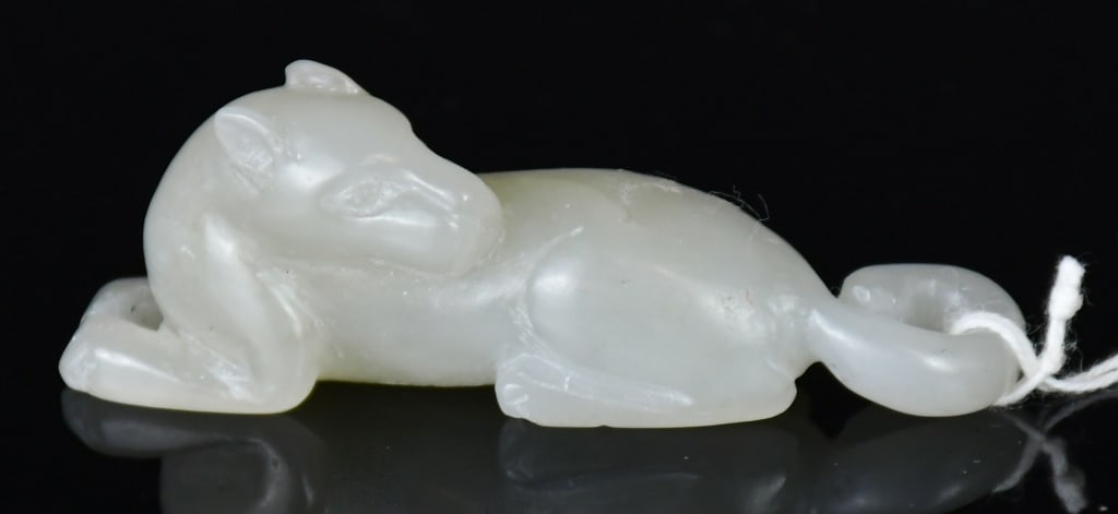 A Jade Carved Dog Republican: A jade carving of a dog in a recumbent position, in celadon-white tone. 5.9x1.6cm 民國 白玉臥犬擺件