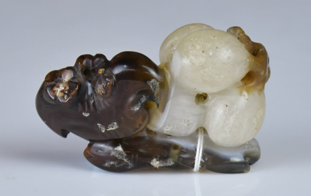A White Jade Carved Bat & Peach Pendant Qing: Carved as a bat beside peaches, the stone of creamy white tone with dark-brown and russet inclusions. 5.1x3.4cm 清 玉雕福壽雙全把件