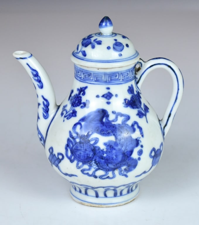 A Blue & White Ewer Qing: Potted with a globular body, a long curved spout, and a loop handle, surmounted by a domed cover with a finial knop. The body is decorated with mythical beast amid scrolling motifs, interspersed with 