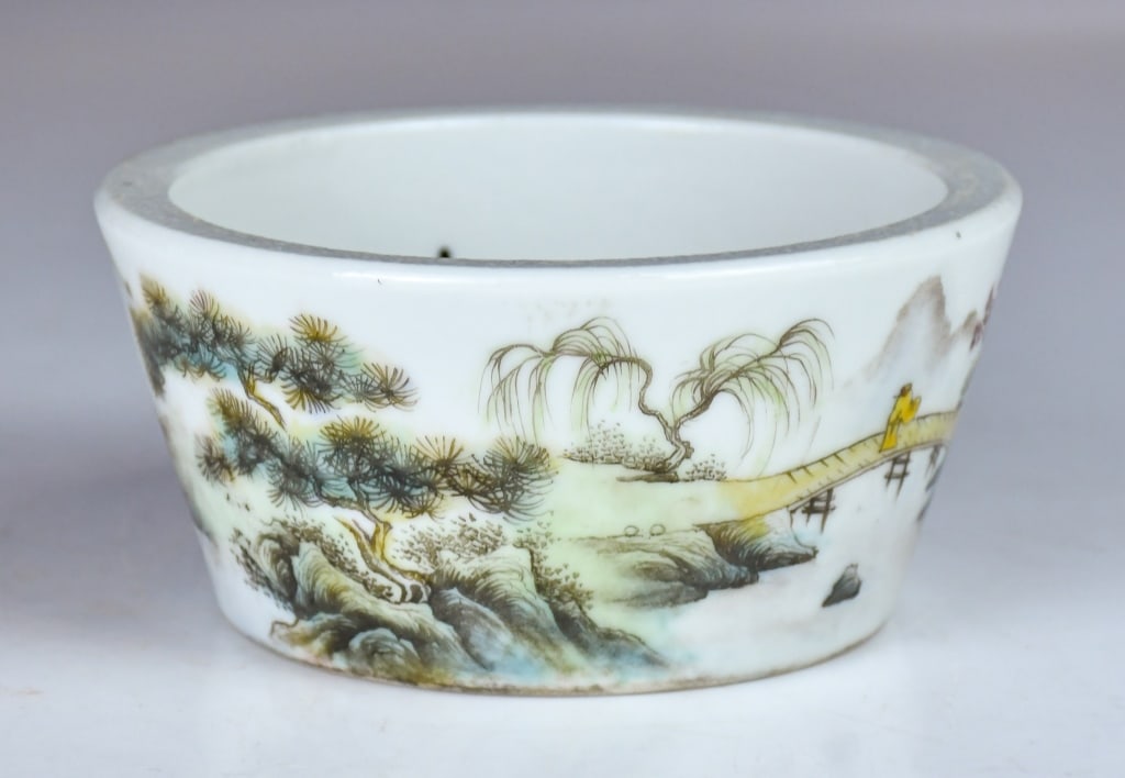A Famille Rose Landscape Washer: Potted with thick, deep sides tapering slightly toward a flat base, terminating in a wide, unadorned rim with a broad lip. The exterior is enameled in a soft palette with a continuous landscape narrat