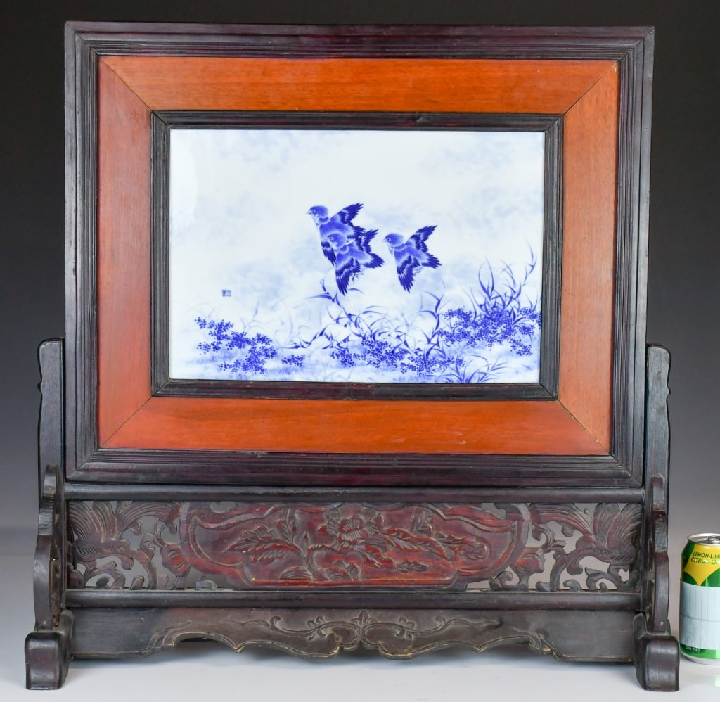 After Wang Bu (1898-1968) Blue & White Plaque: A landscape shape porcelain plaque, depicted birds flying above reeds scene, with artist's signature. Framed in a nice wood stand as a table screen. Plaque size: 37.7x25.9cm, with wood stand size: 62x