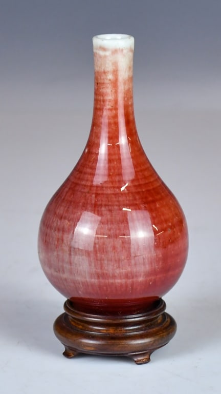 A Peachbloom-Glazed Bottle Vase w/Std 19thC: Potted with a pear-shape body rising to a tall, slender neck. Overall covered in a mottled and speckled peachbloom glaze crushed strawberry tones. The rim is reserved in white, and the glaze stops nea
