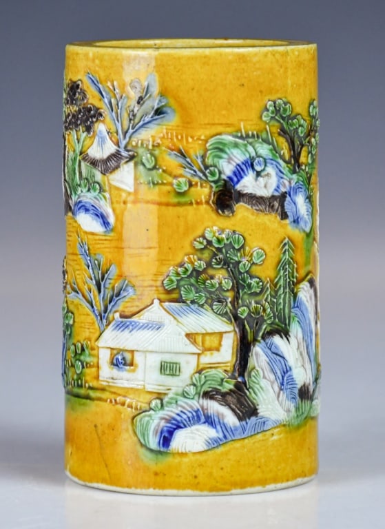 A Sancai-Glazed Landscape Brush Pot w/Mk: Of cylindrical form, the exterior applied with a yellow ground and decorated in relief with a continuous landscape scene depicting pavilions, trees, rockwork and foliage; four-character maker's mark a