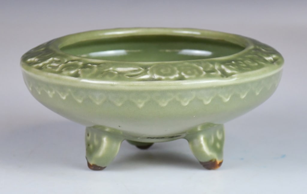 A Longquan Celadon Tripod Censer Qing: The compressed globular body supported on three short feet, covered overall in green celadon glaze, H: 6.5cm, D: 14cm. 清 龍泉三足爐 來源: 多Í