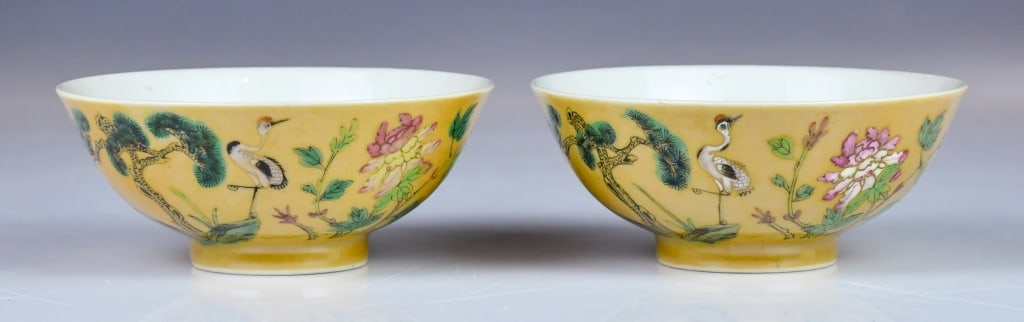 Pair of Famille Rose Yellow-Ground Bowls Qing: Potted with deep, rounded sides resting on a short, straight foot. The exterior is covered in an attractive, slightly mottled yellow enamel ground. Painted in vibrant famille-rose palettes with a cran