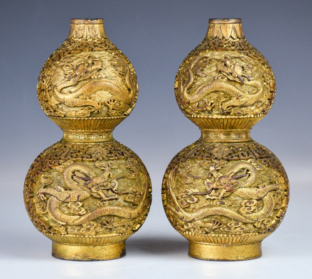 Pair of Gilt Carved Red Lacquer Gourd Vases Qing: The pair of heavily cast vessel are exquisitely sculpted in the form of a double-gourd, the exterior intricately cast in high relief with dragons writhing amidst dense auspicious clouds and floral scr