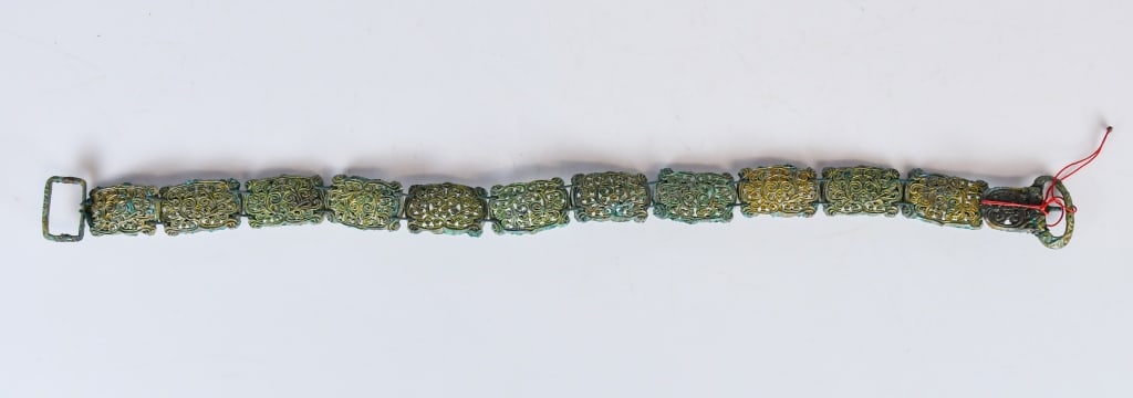A Ming Style Gilt Bronze Belt: Comprising a series of gilt bronze openwork belt plaques, each decorated with scrolling floral motifs, joined together to form the belt, fitted with a buckle and hook terminal, L: 50.5cm.