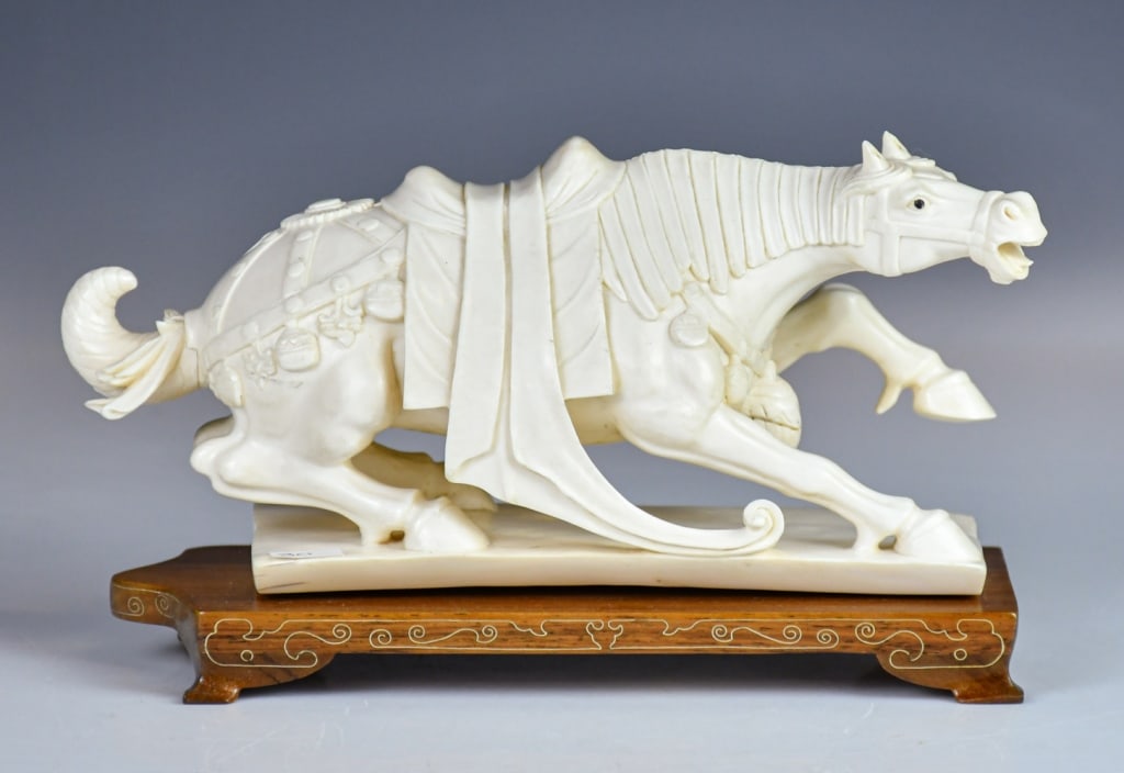 A Bone Carved Horse w/Std 1950-70s: Carved as a galloping horse with its leg outstretched, the body is draped with ribbons, and the hindquarters are detailed with a saddle cloth and ornaments, L: 22.8cm. 建國期 骨