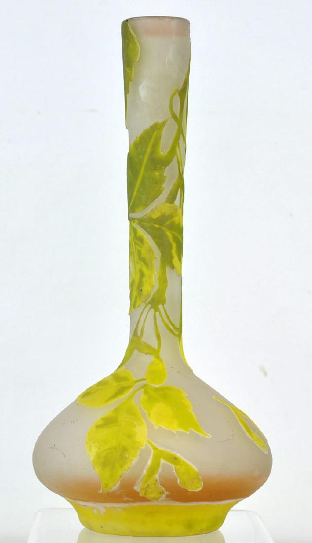 Signed Galle Cameo Glass Bud Vase: Galle cameo art glass vase. Cylindrical vase with raised vines & leaf designs, funnel neck & bulbous base. Signed near base. Measures 8"H X 3.75"W at base. No visible chips or cracks, see photos. In h
