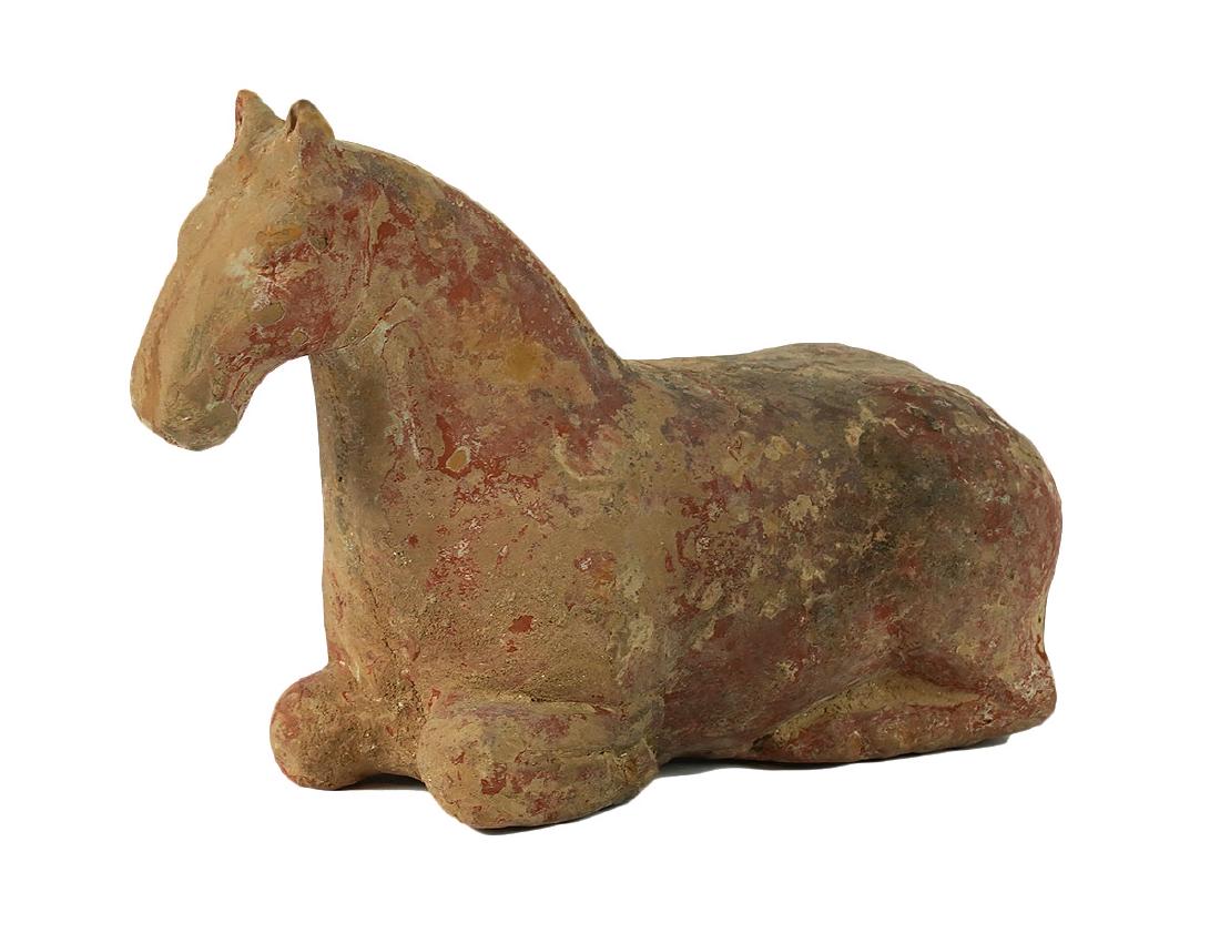 Chinese Tang Dynasty Reclining Terra-Cotta Horse: Chinese Tang Dynasty terra-cotta reclining horse, legs tucked under body. Measures 5.75"L x 4"H x 2 1/8"W. Wear commensurate with age, see photos. Examine all photos closely. Contact AAG for more deta