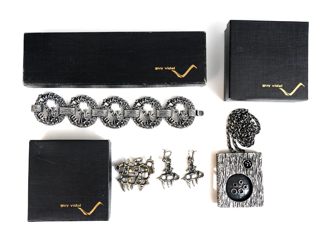 Guy Vidal 4 Pcs. in Original Boxes: Guy Vidal 'Open Circles' pewter bracelet, 7"L x 2.25"W; open work pewter brooch and matching earrings; 2 sided 'Shadow Box' pendant on 28" chain, all in original boxes. Good condition, see photos. Exa
