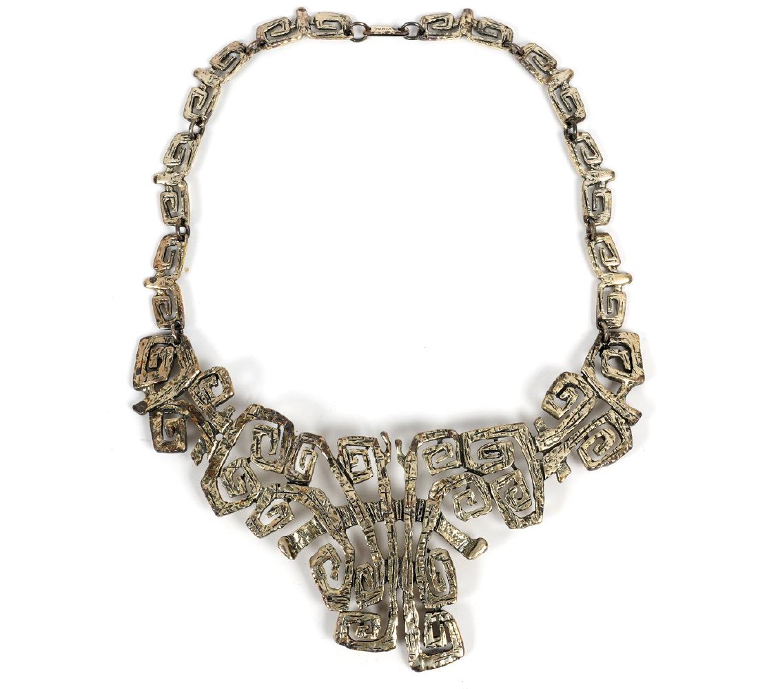 Guy Vidal Squared Curlicue Bib Necklace: Guy Vidal bib necklace in plated pewter, squared curlicue design. Marked Vidal on clasp and marked on inside. Measures approximately 15" wearable; center piece is 5 3/8" x 2.5". Good condition, see ph