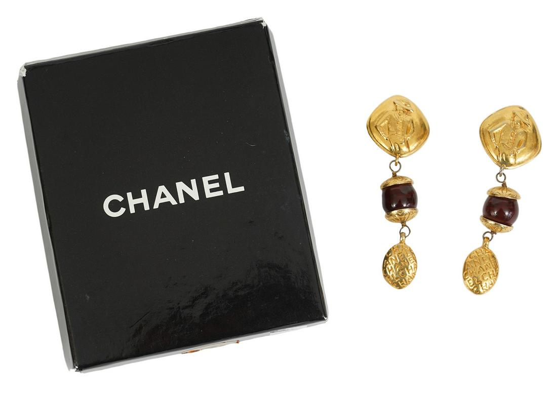 Chanel Gold Mlle Coco Red Gripoix Earrings 1970s: Chanel gold earrings with Mademoiselle Coco on the top and dangling with red Gripoix. Vintage 1970 clip on earrings comes with Chanel box. Round cartouche marked Chanel France. Earrings measures 2.75"
