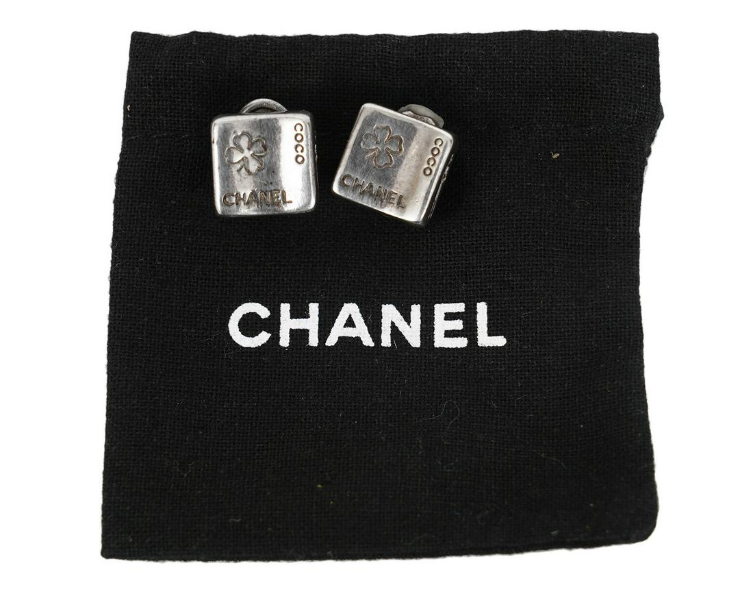 Chanel Sterling Silver Square Clip On Earrings: Chanel clip on earrings in 925 sterling silver. The front is engraved with a 4 leaf clover and 'Coco Chanel'. On one side is a silhouette of Coco and on the other side says Paris. Measures 1/2" x 1/2"