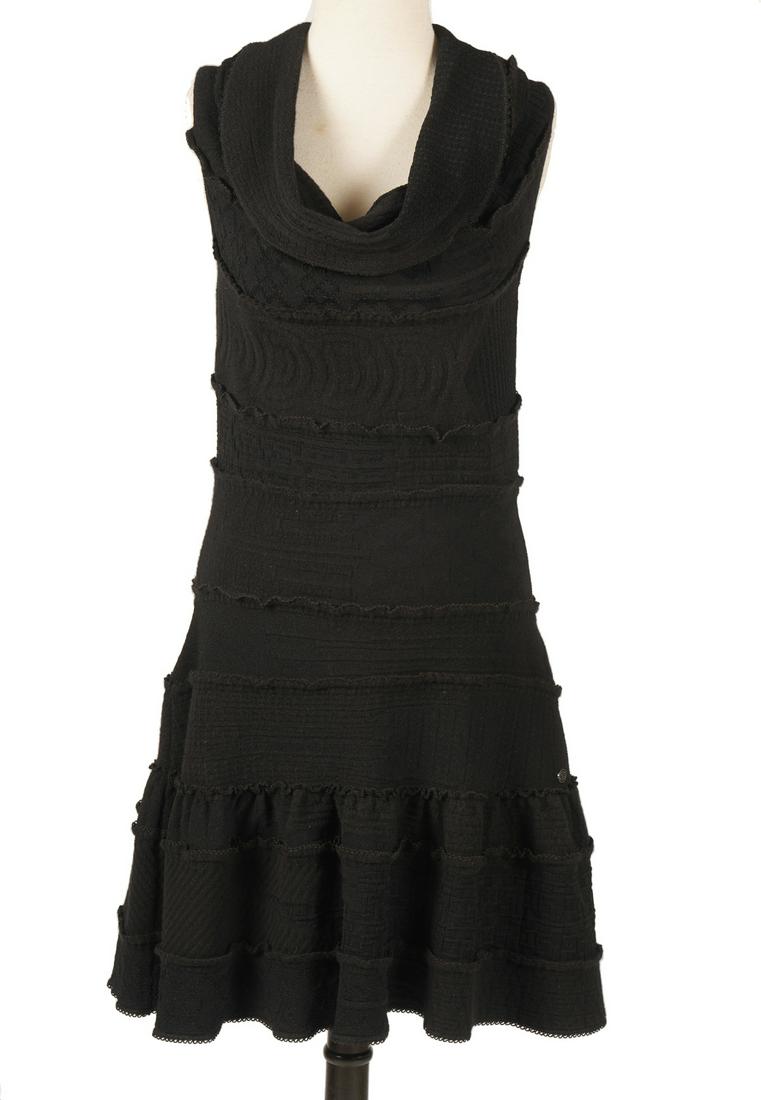 Chanel Wool Blend Little Black Sweater Dress 40: Chanel new with tags black stretch wool blend sweater dress with draped neckline, sleeveless, size 40. Accented with oval enameled CC medallion. Fitted body with flared skirt. Measures bust 34" (un-st