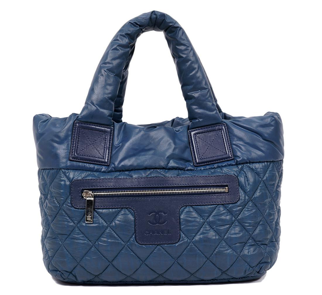 Chanel Cocoon Blue Quilted Pillow Bag 2009: Chanel Cocoon tote bag in quilted blue parachute nylon featuring a hook closure, black leather accents and front zipper pocket. Lined in black nylon with an inside zipper pocket. 12"L x 8.5"H x 6"W. M