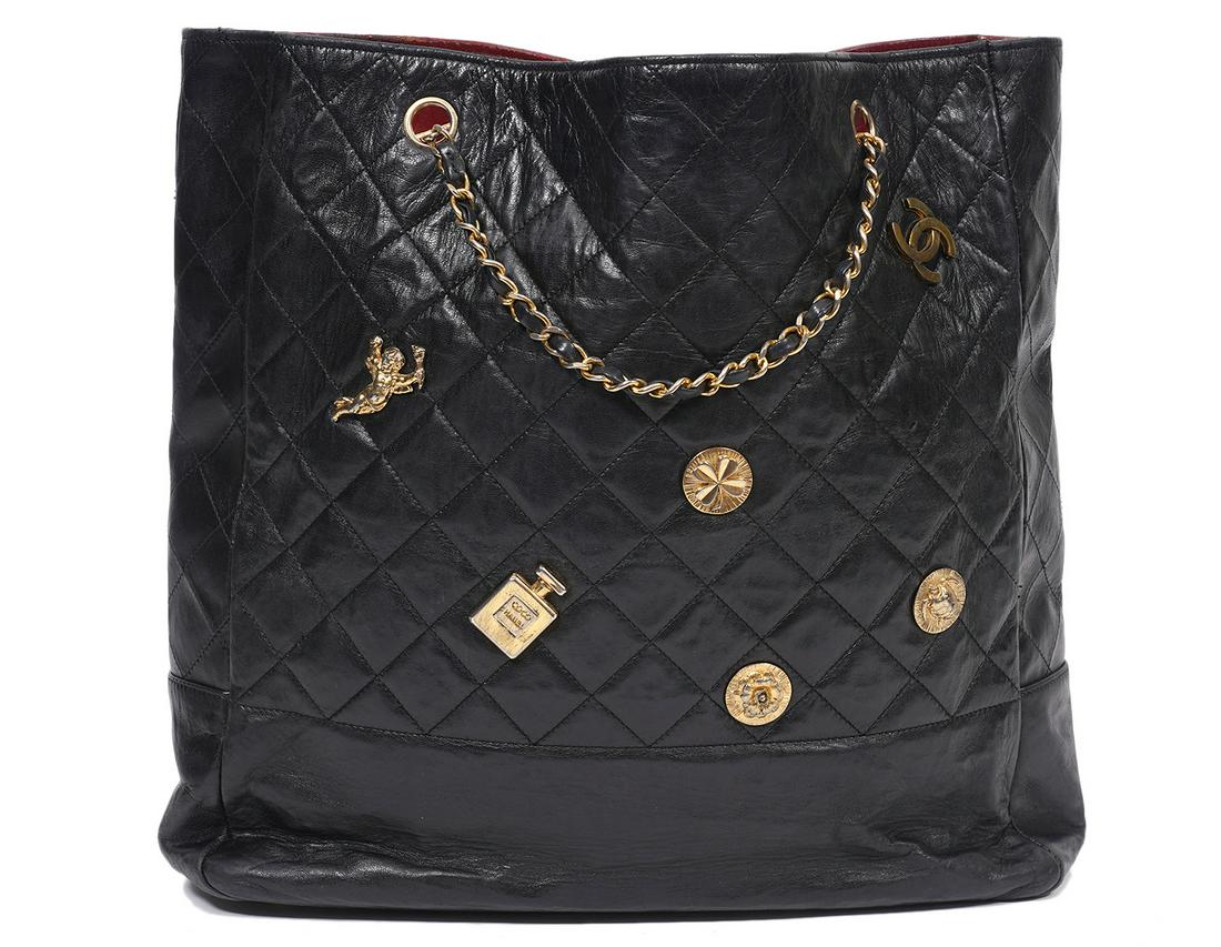 Chanel Black Vintage Quilted Tote & Charms: Chanel large black quilted vintage tote with leather laced toggle chain straps featuring iconic Chanel charms (four-leaf clovers, pumps, perfume bottles, camellias). Lined in burgundy leather with 2 z