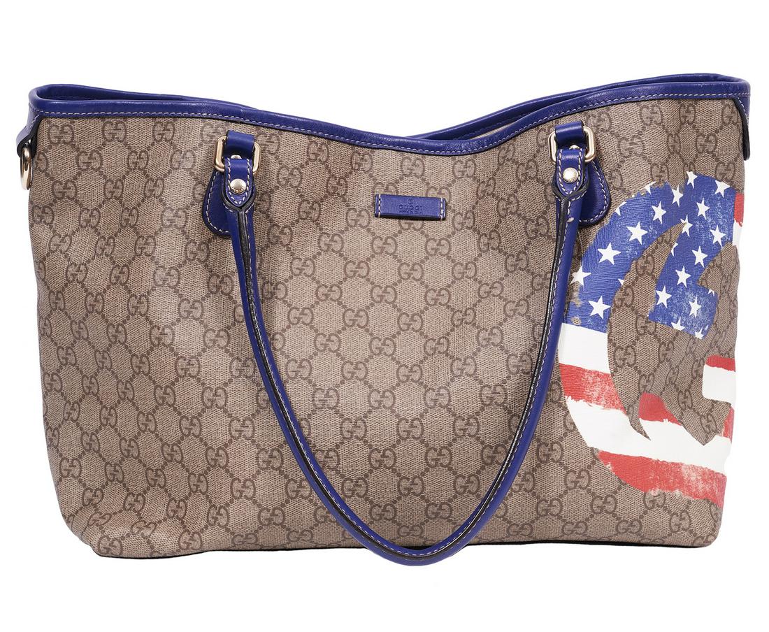Gucci Monogram UNICEF Joy Tote: Gucci UNICEF Joy tote with red, white and blue stars and stripes GG and accented with royal blue leather trim and rolled handles. Lined in beige canvas with a zipper pocket inside. 13.5"L x 10.5"H x 6