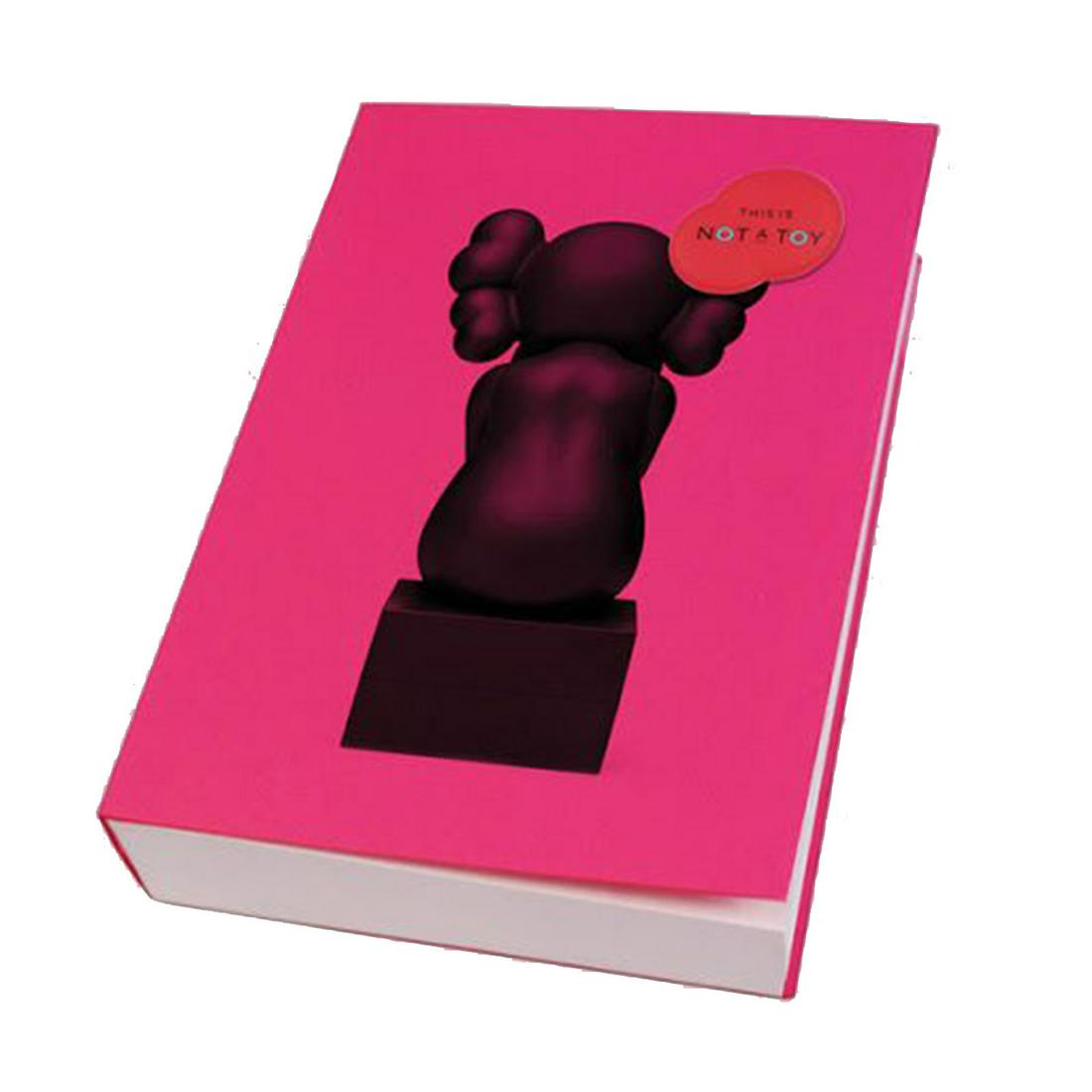 KAWS 'This Is Not A Toy' Sealed Paperback: KAWS sealed paperback 'This Is Not A Toy', guest curated by Pharell Williams, a 2015 survey of contemporary art & collectible design inspired by the Design Exchange Exhibition. Measures 8"L x 5"W x 1.