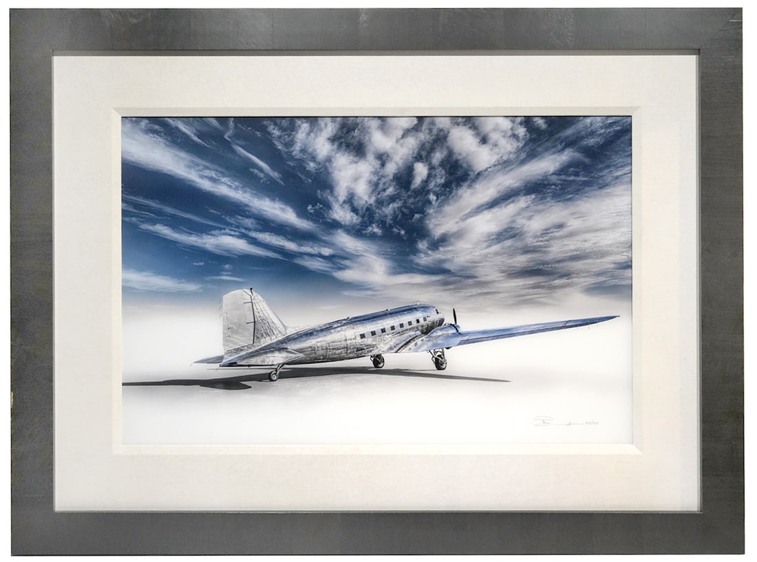 Peter Lik 'Dreams Edge' Photograph Print: Peter Lik, Australia, (Born 1959). 'Dreams Edge' panorama, photograph print of a vintage WW II Silver DC-3 aircraft taken in Oregon. It is signed and numbered lower right 404/450, mounted in a black w