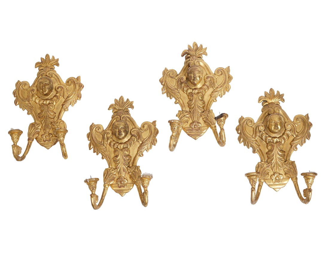 Set of Four19th C Carved Gilt Wood English Sconces: Set of four 19th C carved gilt wood 2 arm sconces with a mascaron in the center surrounded by ornate scrolled leaf and floral designs. Provenance: From the estate/collection of Michael Kittredge II, f