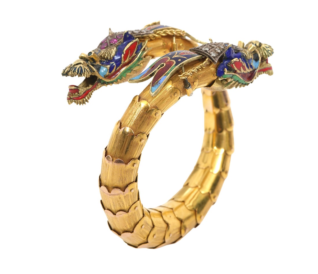 18K YG Diamond, Emerald, Sapphire Dragon Bracelet: 18K yellow gold (tested, not marked) flexible bangle bracelet with 2 multi-color enamel dragon heads. One dragon head is set with diamonds and rubies and has emerald eyes. The other head is set with d